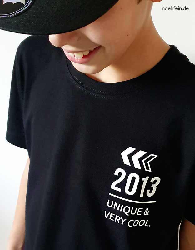 Geburtstagskind trägt personalisiertes T-Shirt mit Geburtsjahr Zahl - Vorderansicht schwarzes Shirt mit weißer Folie